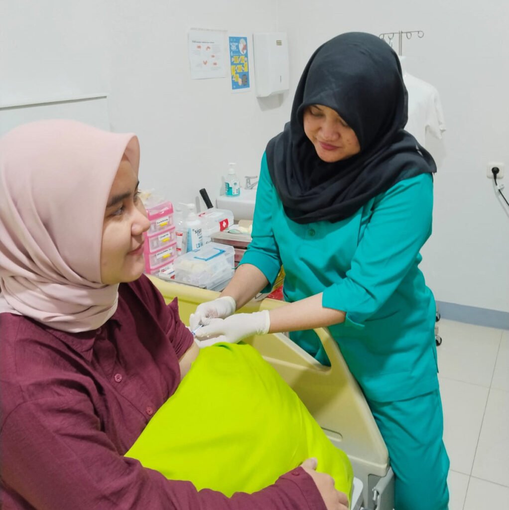 Tenaga medis sedang memberikan suntikan vaksin kepada pasien.